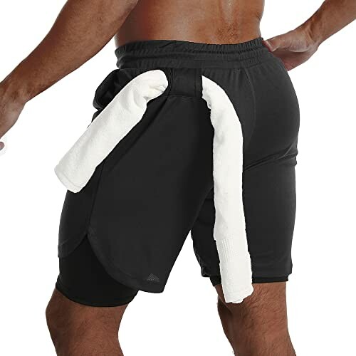 Person wearing black athletic shorts with a towel looped through.