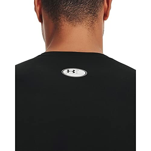 Back view of a black T-shirt with a logo near the neck.