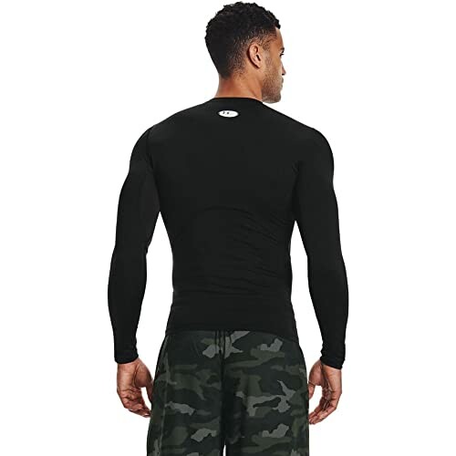 Man wearing a black long-sleeve compression shirt and camo shorts, viewed from the back.