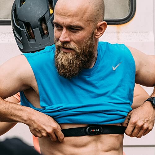 Man in blue sleeveless shirt adjusting a Polar heart rate monitor.