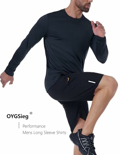 Man wearing a black long sleeve shirt and shorts in an athletic pose